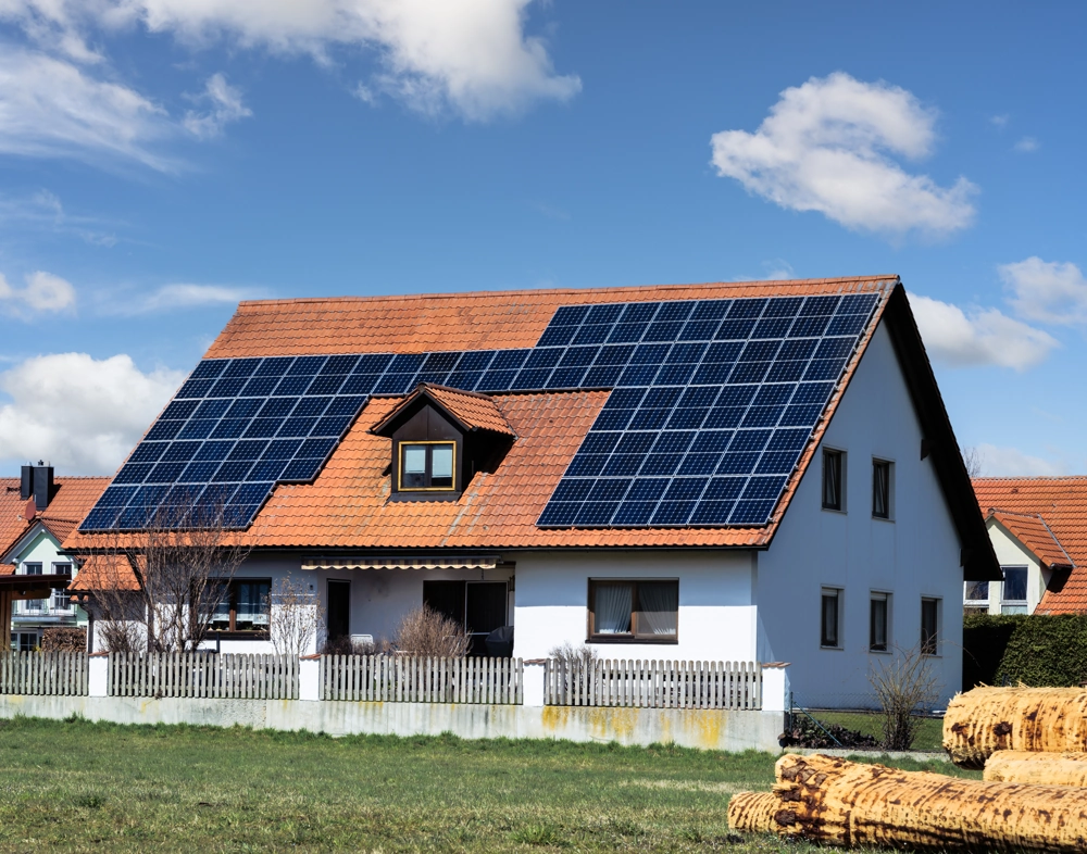 Hausdach mit Photovoltaik Montage auf roten Ziegeln vor blauem Himmel